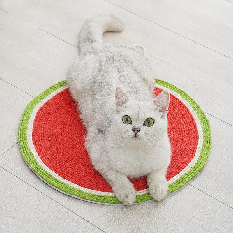 White cat using a watermelon-shaped cat scratching mat